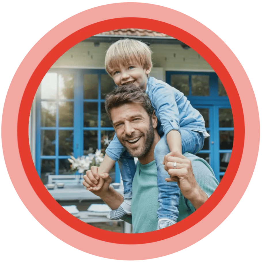 Smiling child sitting on his father's shoulders.